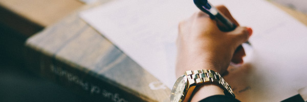 Photo of a woman writing with her left hand on a pad of paper