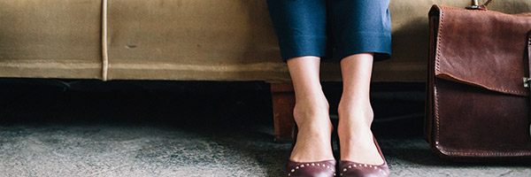 Photo of a person sitting on a couch with their bag next to them on the floor