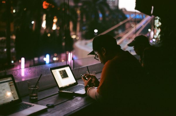 Man checking his phone while his laptop is open