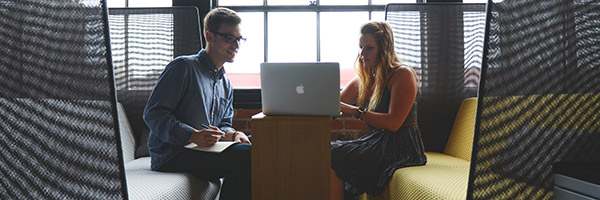 Man and woman looking at a Macbook