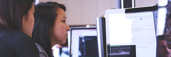 Two women looking at code on a computer